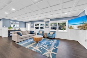 Relax in this stylish living room with a sofa, chair, and coffee table, surrounded by natural light and recessed lighting.