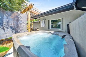 Relax in a hot tub surrounded by a shaded pergola.