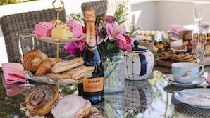 Une table dressée à l’extérieur, avec de la nourriture, des boissons et une bouteille de Canti Prosecco.
