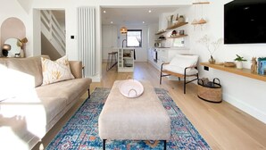 A modern living room with a sofa, ottoman, and a dining area with a table and chairs.