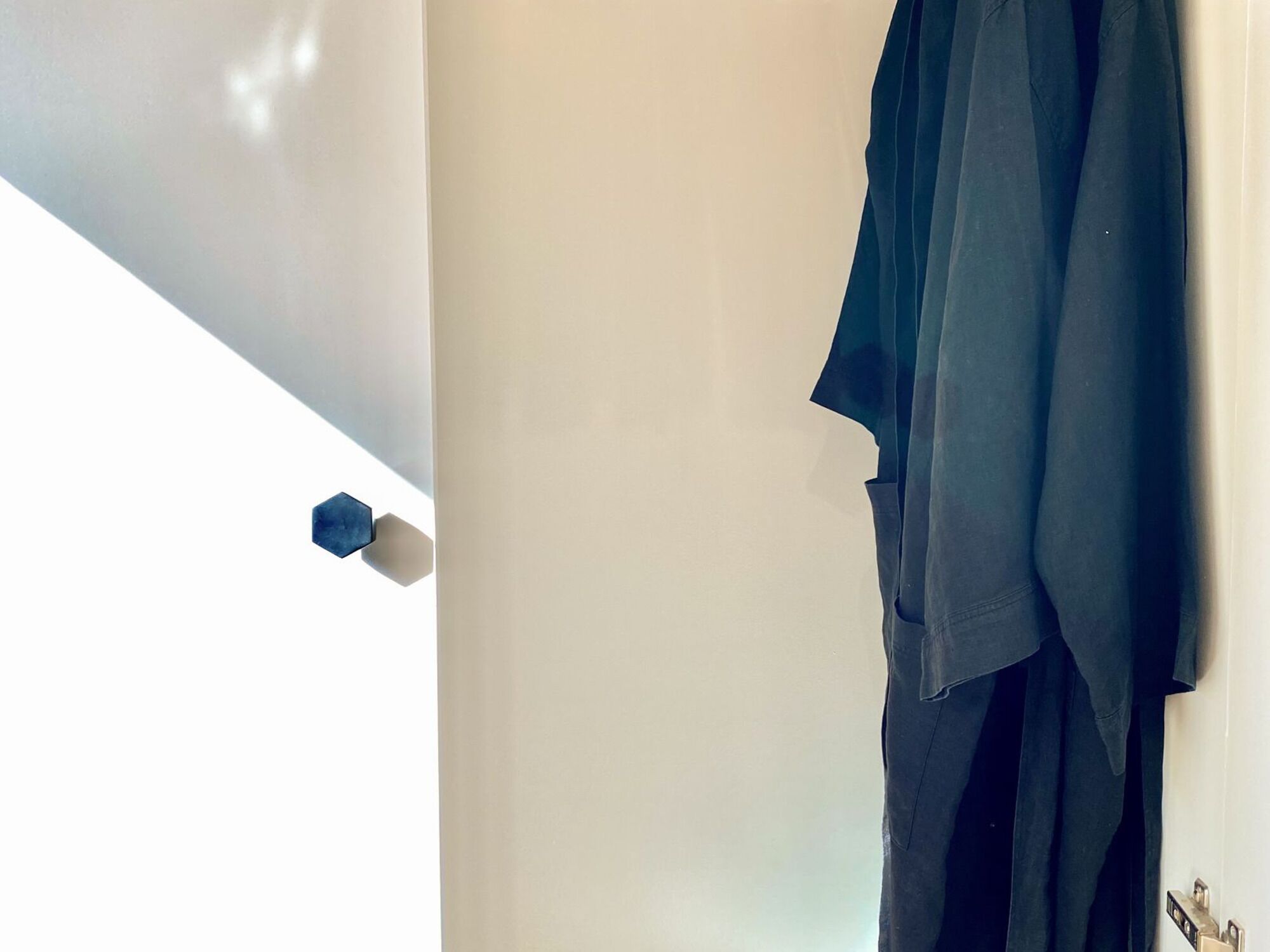 Una habitación con una pared blanca y una puerta con picaporte azul.