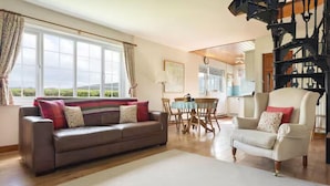 A living room with a sofa, armchair, dining table, and a staircase. - The Old Telephone Exchange Cartmel - Pass the Keys (Cartmel)