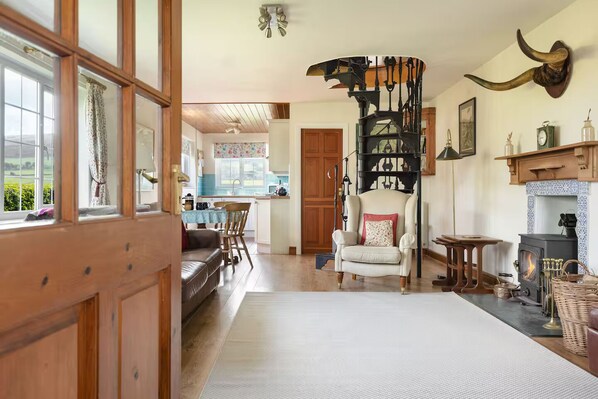 A cozy living room with a fireplace, a dining area, and a kitchen visible through an open door.