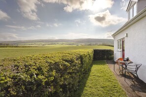 A house with a view of a green field and hills.