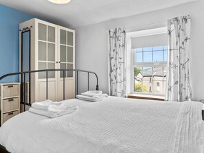 Une chambre à coucher avec un lit, une armoire et une fenêtre avec des rideaux.