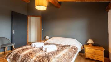 A bedroom with a large bed, wooden nightstand, and a chair.