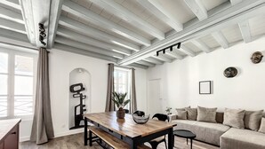 A modern living room with a wooden dining table, a sofa, and a large window. - Appartement au Coeur de Ville (Sens)