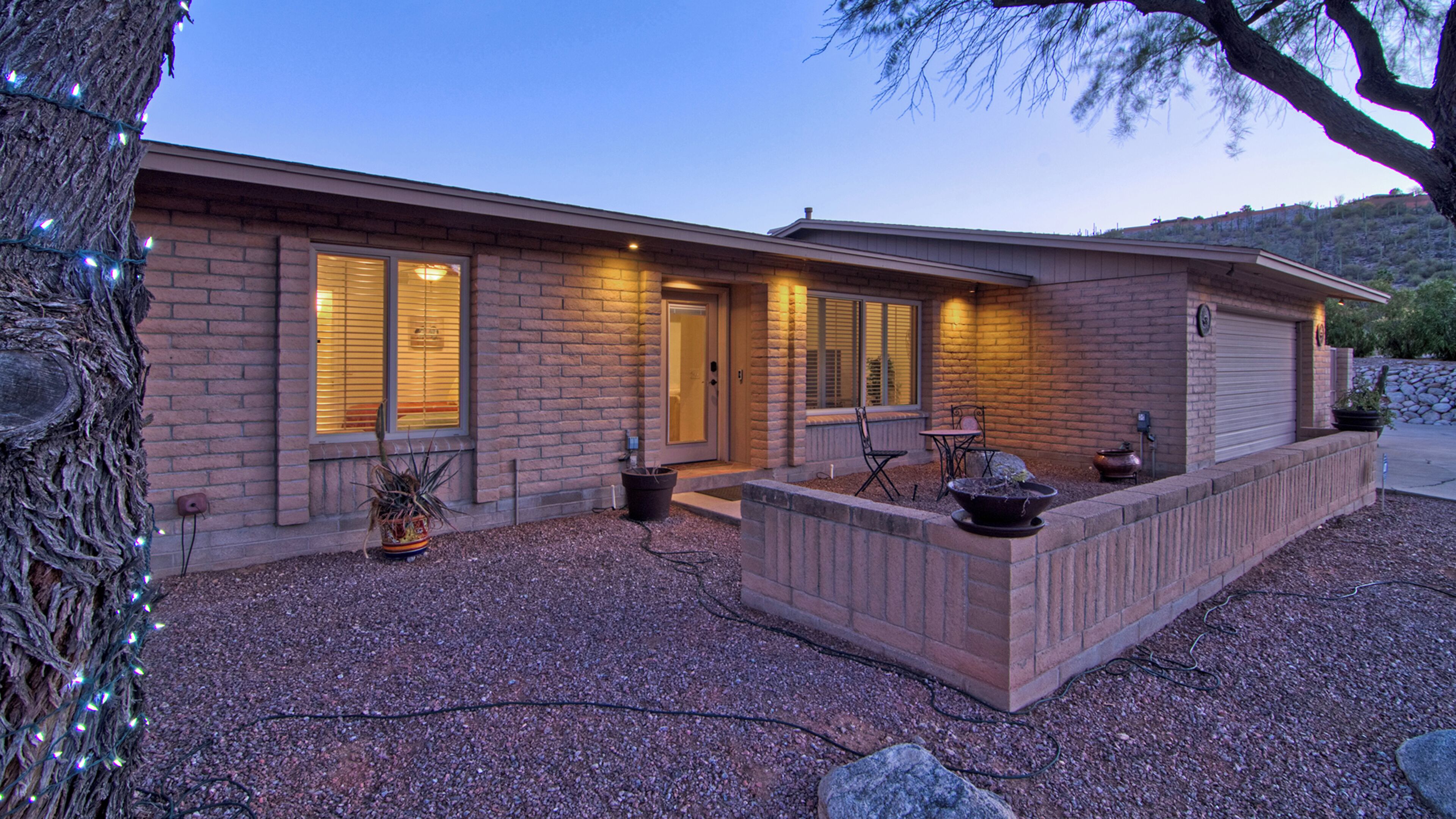 A modern house with a brick exterior, a front porch, and a gravel driveway.