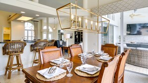 Un coin repas avec une table en bois dressée pour six personnes, entourée de chaises en osier.