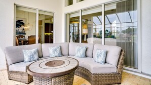 Un coin salon avec un canapé incurvé, une table ronde et de grandes portes vitrées donnant sur une terrasse extérieure.
