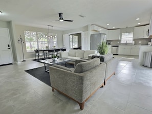 A spacious living area with a sofa, coffee table, and dining table set. - Darren’s Den: Sleeps 8! 4Bd/2Bth/Garage Modern Home (Jacksonville)