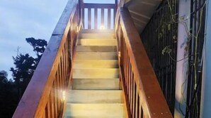 Un escalier en bois, doté d’une rampe, qui mène à l’entrée d’un bâtiment.