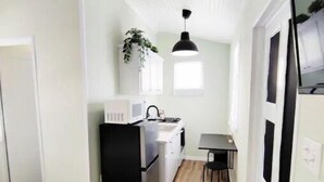 Une pièce de taille modeste comprenant un lit, une petite kitchenette, un coin repas et une fenêtre.