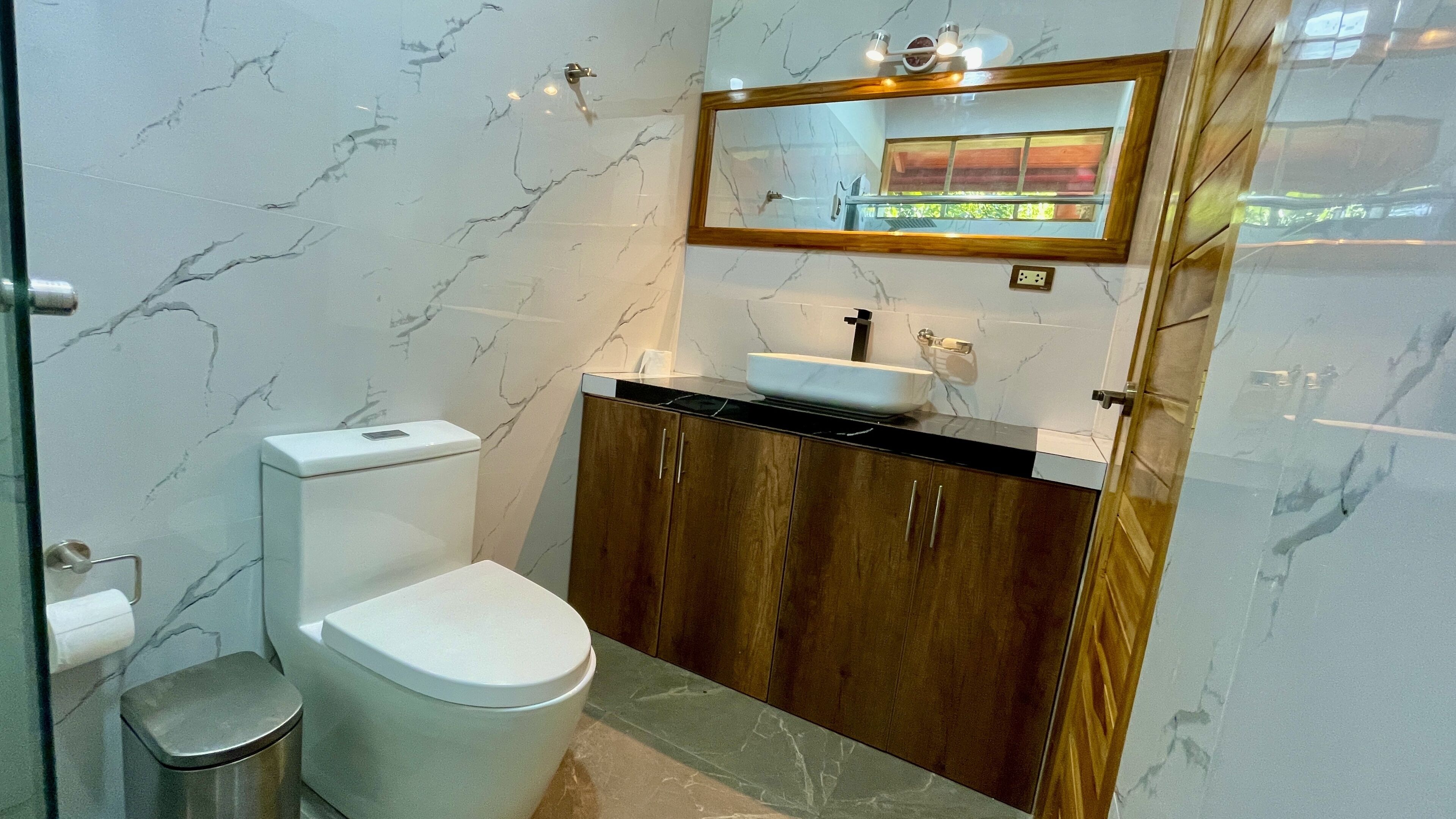 Een badkamer met een toilet, een wastafel en een spiegel erboven.