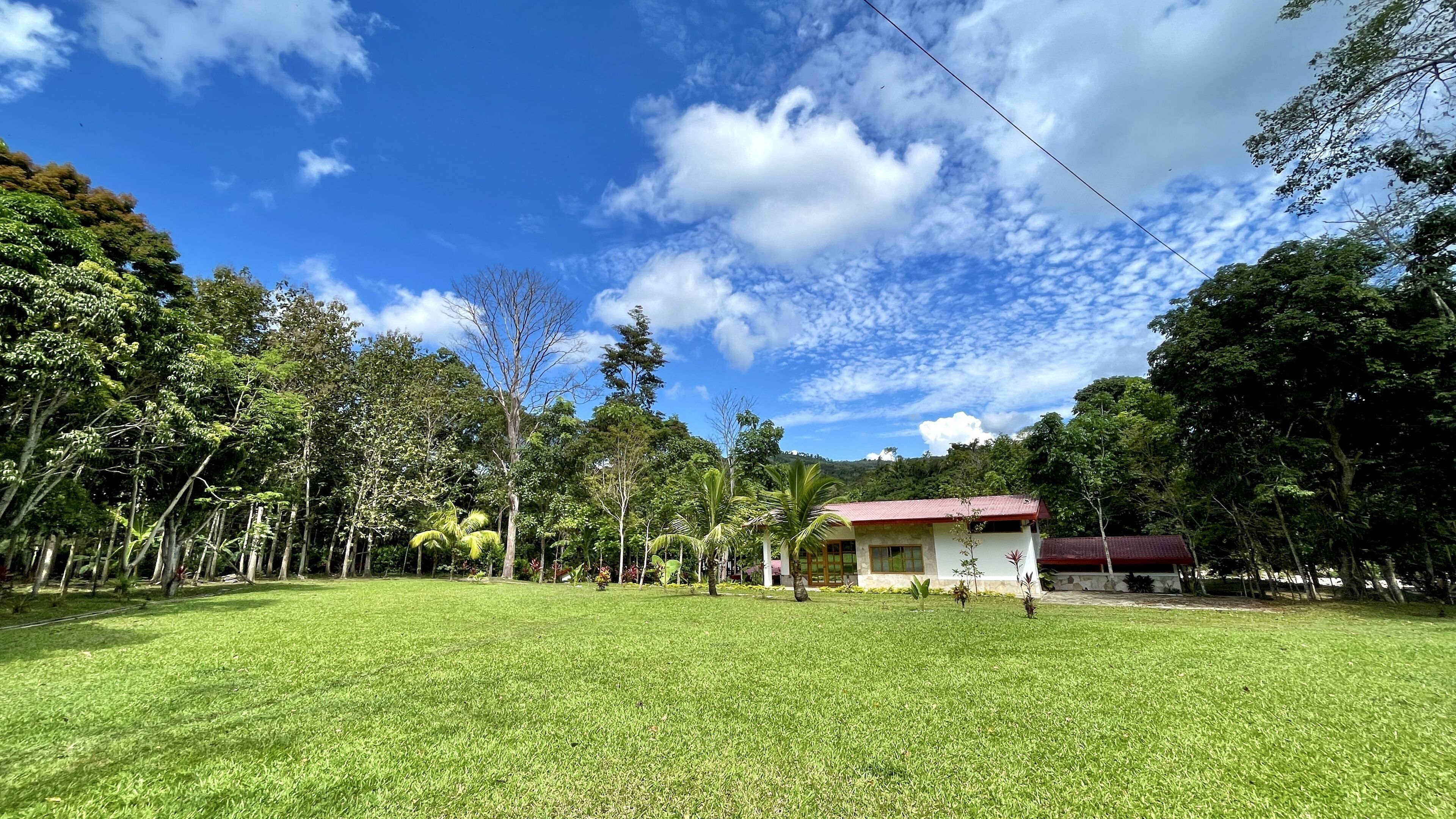 A grassy area with a building that has a red roof.