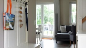 Un salon moderne avec un banc intégré, un fauteuil gris et une vue sur l’extérieur.
