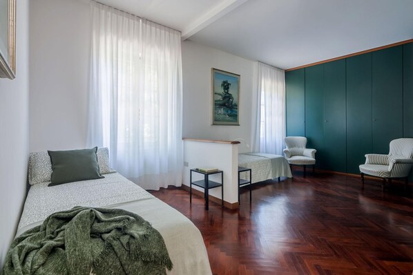 Habitación de hotel con cama, dos sillas, una mesita y un cuadro en la pared.