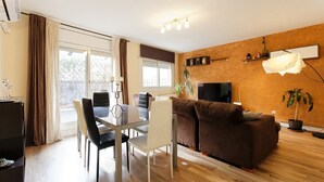 Ein modernes Wohnzimmer mit Essbereich, einer Couch, einem Fernseher und einer Pflanze.