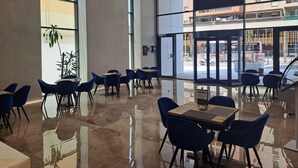 A modern dining area with large windows, reflective floors, and blue chairs.