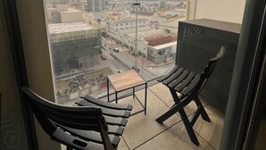 A balcony with two chairs, a small table, and a city view.