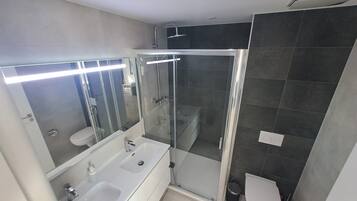 Et moderne badeværelse med bruseniche, dobbelt vask og toilet.
