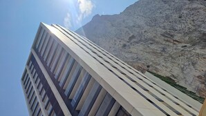 A modern building with a geometric facade and large windows, set against a mountainous backdrop.