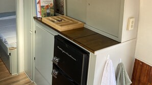 A compact kitchen with a built-in refrigerator, a microwave, and a wooden countertop.