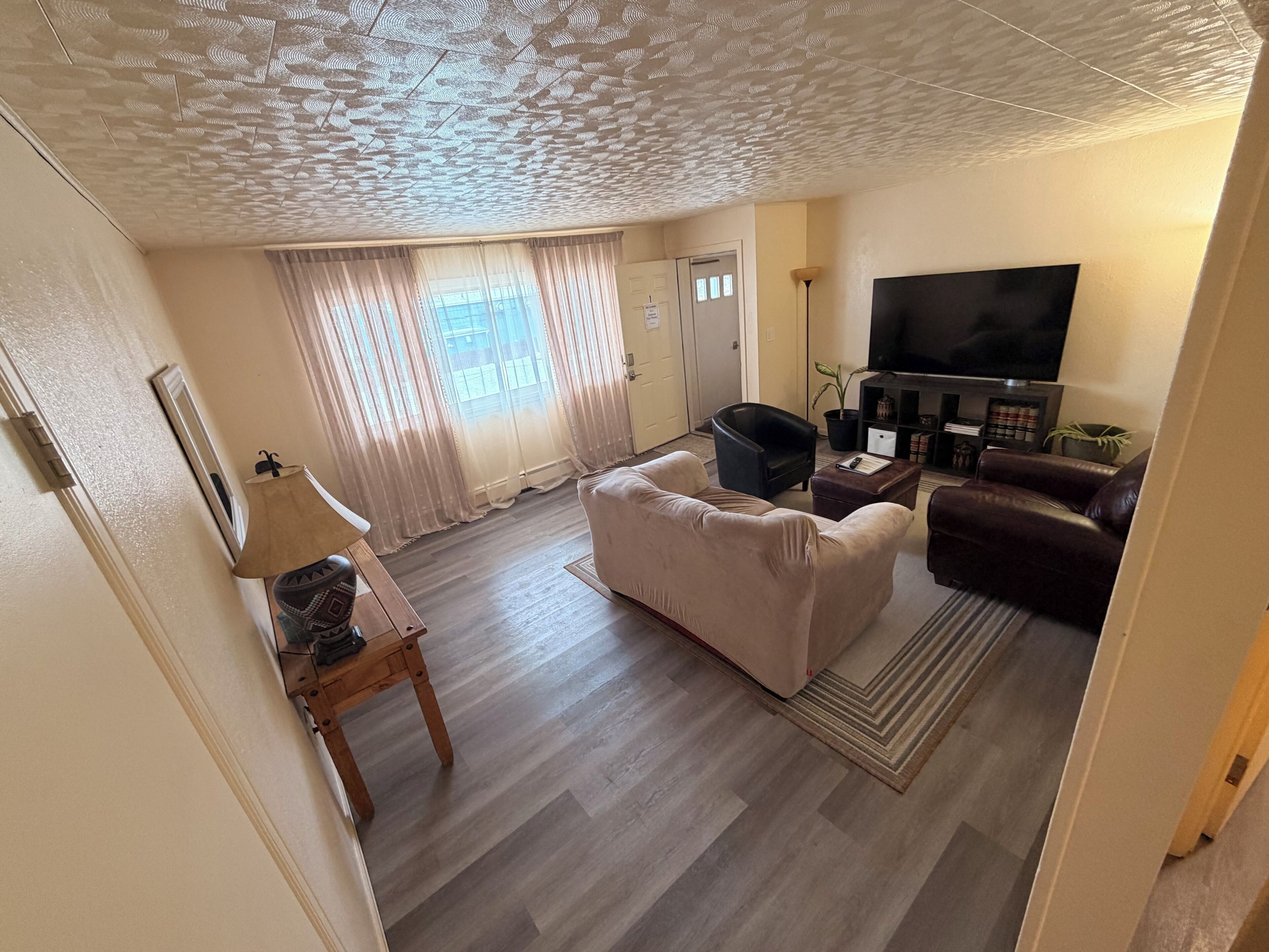 Ein Wohnzimmer mit Sofa, Sessel, Fernseher und Bücherregal.