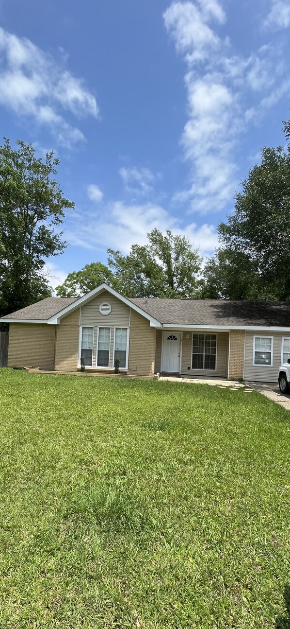 A single-story house with a front porch, a garage, and a well-maintained lawn. - Springdale house  (D'Iberville)