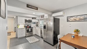 A modern kitchen with white cabinets, stainless steel appliances, and a wooden dining table. - 8/19 now available Updated 2br Minutes from downtown- backyard & Firepits

 (Colorado Springs)