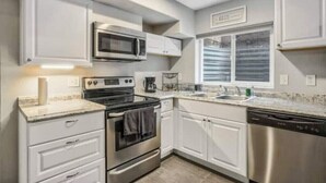 A modern kitchen with white cabinets, stainless steel appliances, and a window with blinds. - 8/19 now available Updated 2br Minutes from downtown- backyard & Firepits

 (Colorado Springs)