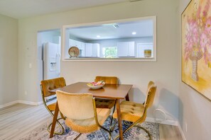 Un comedor con una mesa rectangular, cuatro sillas y un cuenco de fruta.