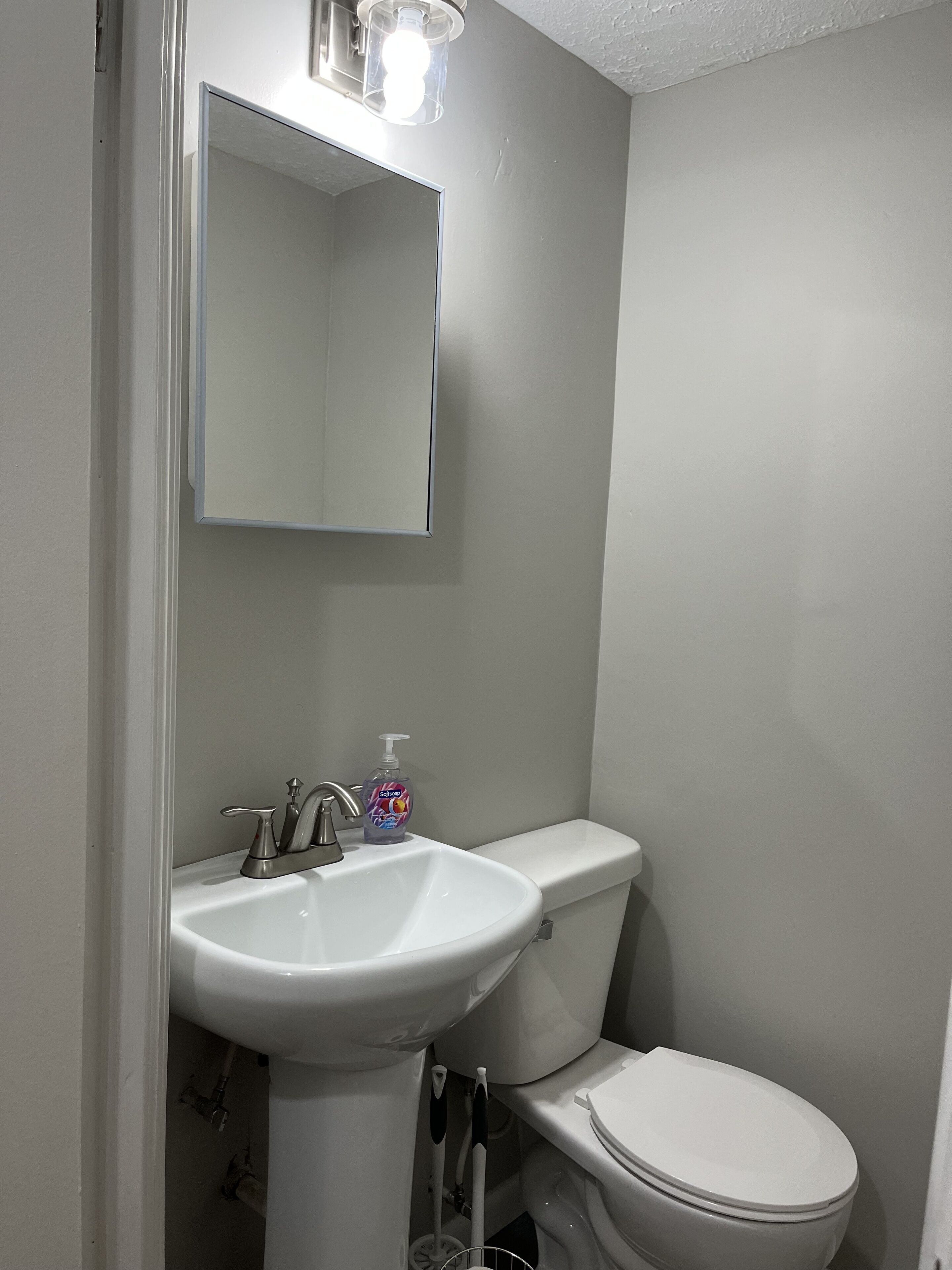 Une salle de bain avec un lavabo blanc, des toilettes et un miroir au-dessus du lavabo.