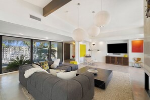 A modern living room with a grey sectional sofa, a coffee table, and a flat-screen TV mounted on the wall.