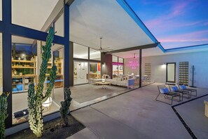 Een modern huis met een ruime patio, een eethoek en een woonkamer.