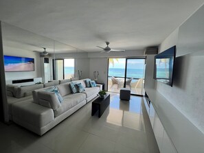 Relax in this stylish living room with a sofa, coffee table, and flat-screen TV, offering a balcony with ocean views.