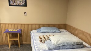 A bedroom with a bed, a small wooden stool, and a framed collage on the wall. - Studio Apartment  (Willmar)