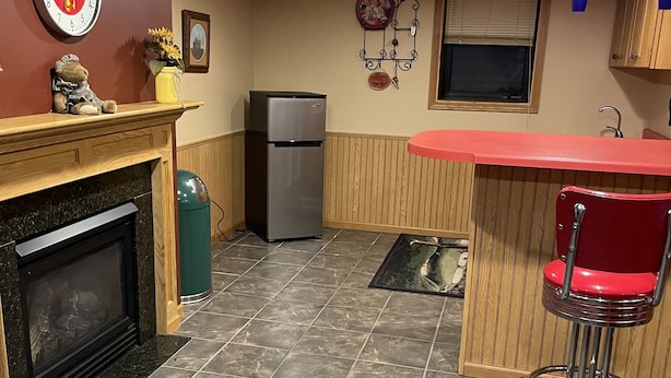 A kitchen with a refrigerator, a sink, a wooden counter, and a red chair. - Studio Apartment  (Willmar)