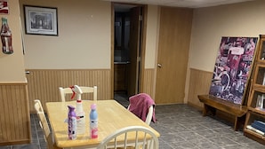 A dining area with a wooden table and chairs, a painting on the wall, and a door leading to another room. - Studio Apartment  (Willmar)