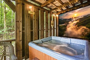 Une cabane en bois avec un jacuzzi, entourée d’une forêt.
