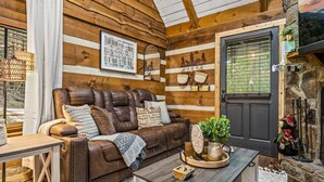L’intérieur d’un chalet confortable, avec un canapé en cuir, une table basse en bois et une cheminée.