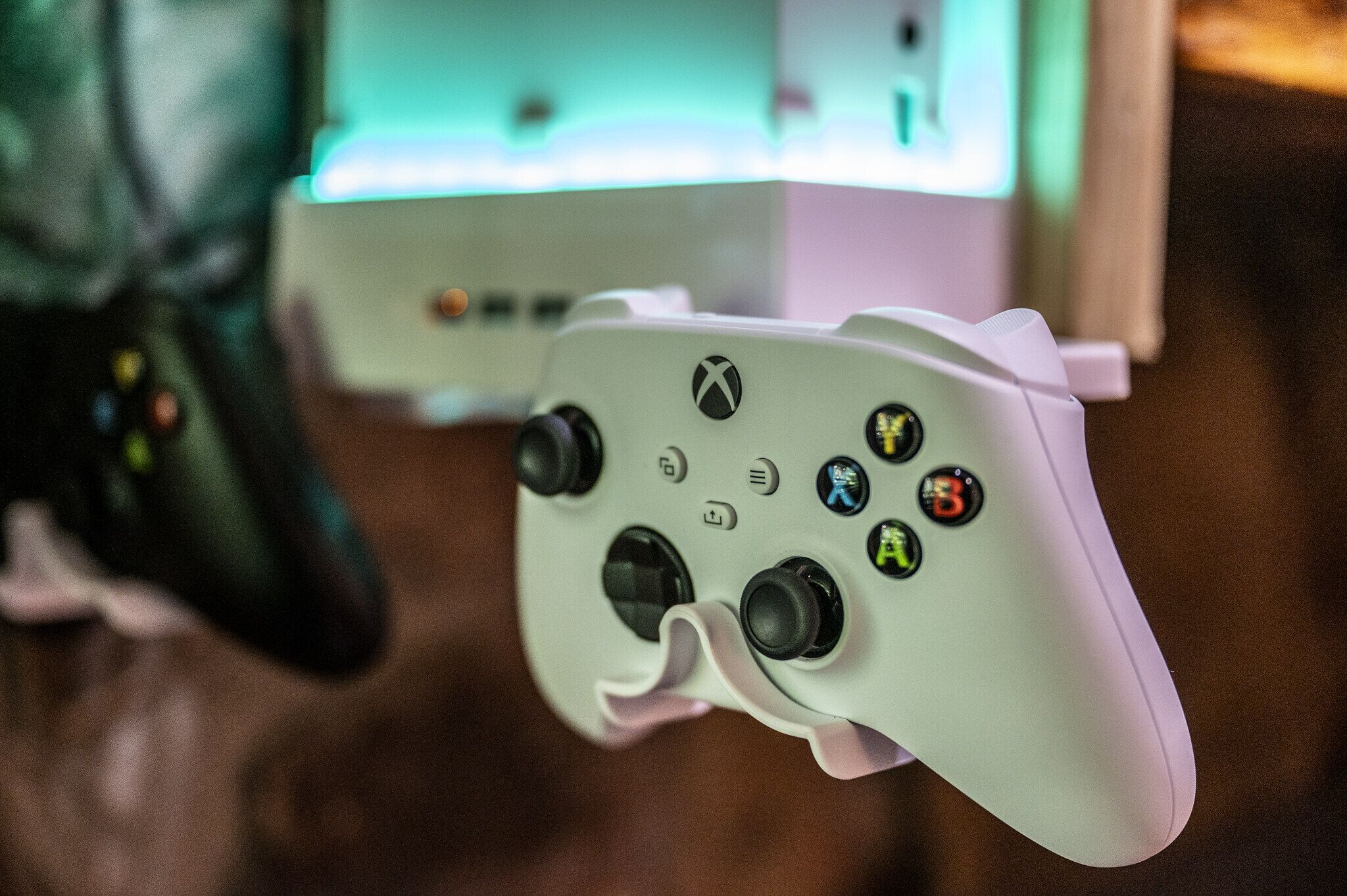 Un controller Xbox bianco con un accento rosa e pulsanti colorati.