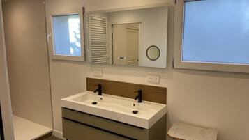 A modern bathroom with a white sink, wooden vanity, and a mirror above it.