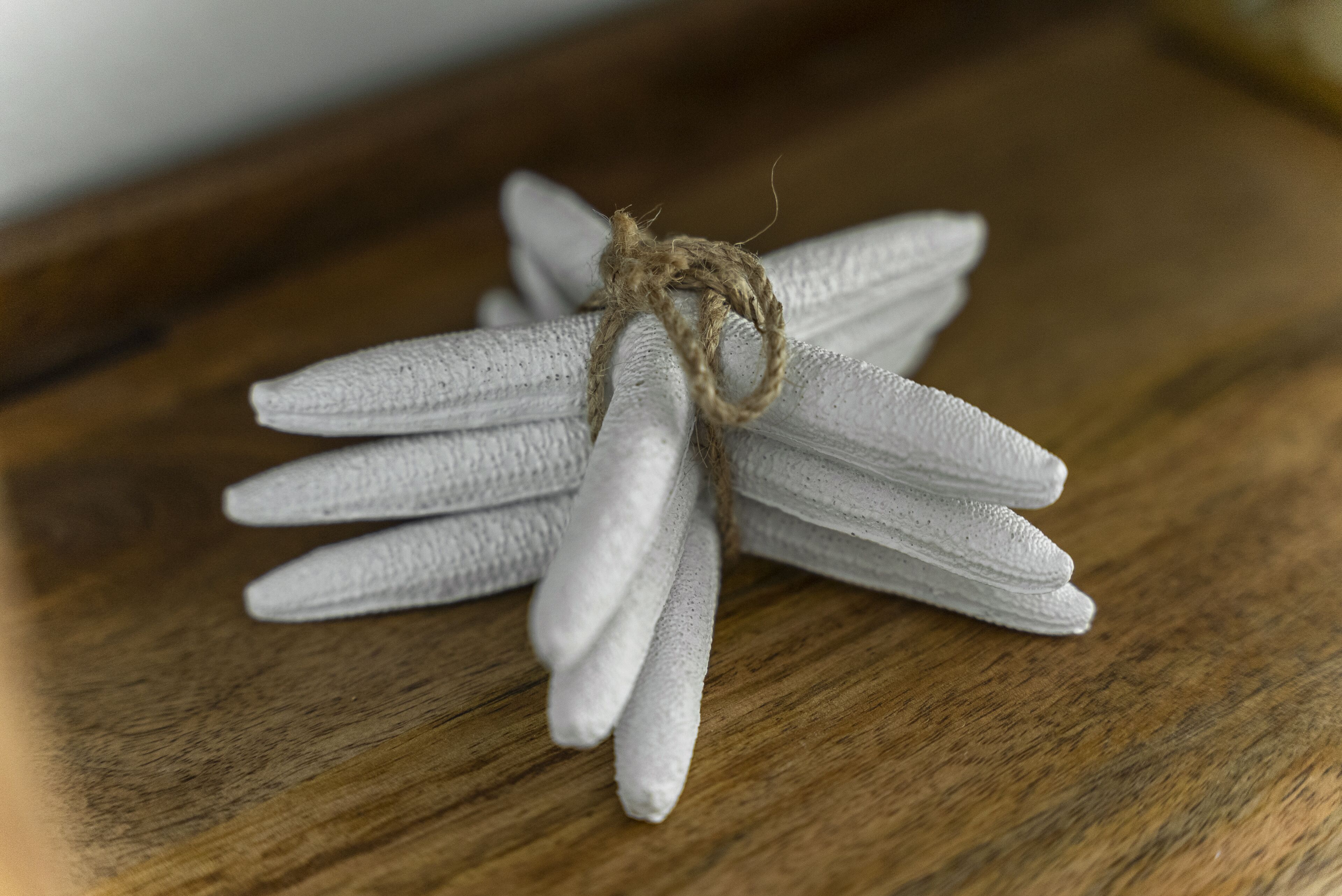 A bundle of white, textured fabric items tied together with a natural fiber rope, placed on a wooden surface.