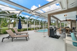 Un espace extérieur abrité comprenant des chaises longues, un barbecue et une piscine.