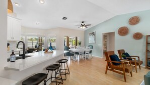 Una cocina amplia con una isla grande, taburetes de bar y un comedor con sillas y una mesa.