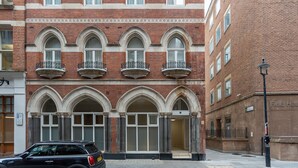 Un edificio de varios pisos con ventanas arqueadas y fachada de ladrillo.