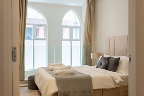 Une chambre avec un grand lit, une table de chevet et une fenêtre avec des rideaux.