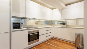 Una cocina moderna con armarios blancos, electrodomésticos de acero inoxidable y piso de madera.