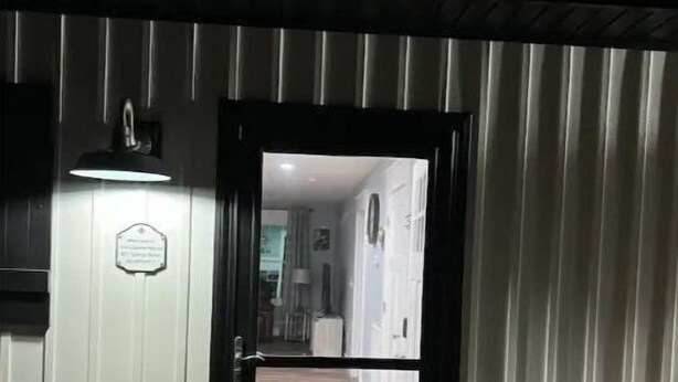 Un umbral que da a un pasillo con piso de madera y un tapete. Hay dos cubetas en el suelo, una a cada lado de la puerta.